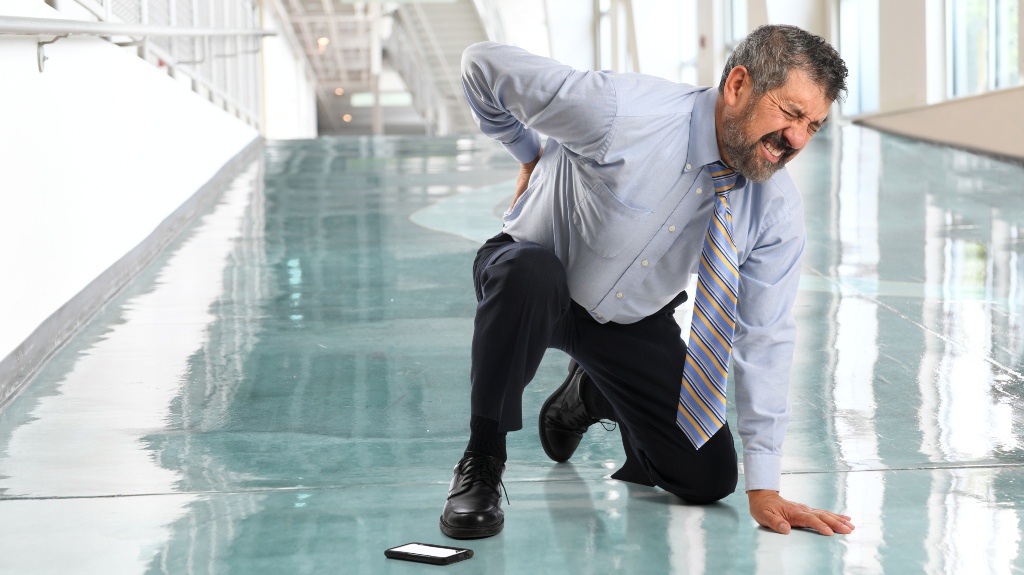 businessman suffering from back injury in office lobby