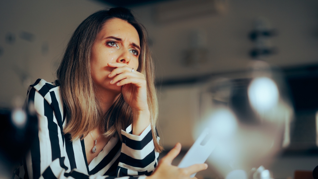 sad woman holding phone in hands