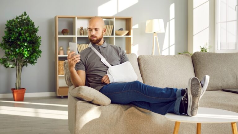 Man with broken arm using mobile phone