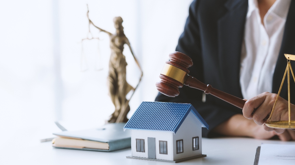 Lawyer holding gavel near house model