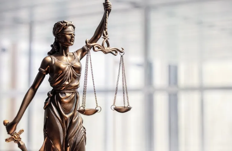 Bronze statue of Lady Justice blindfolded, holding scales in one hand and a sword in the other.