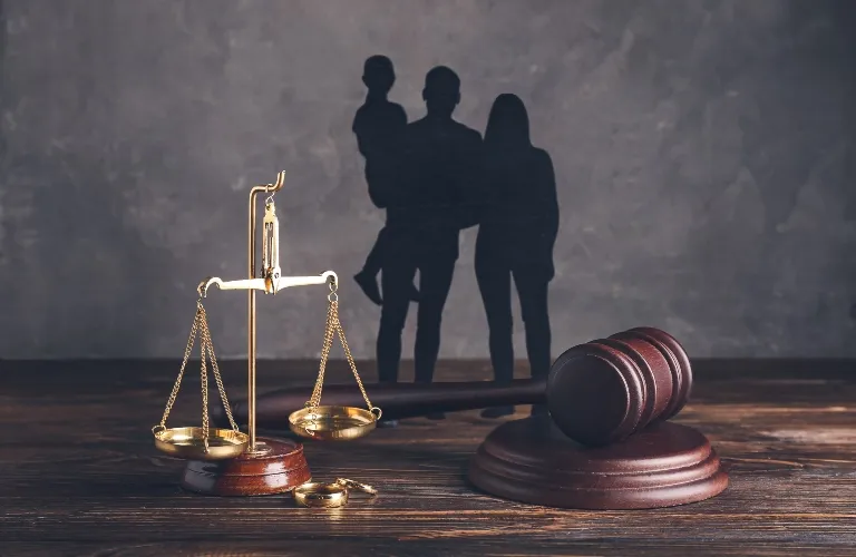 Wooden judge's gavel and golden scales of justice with family silhouette shadow background.